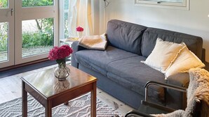 Una sala de estar moderna con un sofá gris, una mesa de centro de madera y un florero de vidrio con flores.
