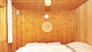 A wooden-paneled room with a bed, a wall-mounted fan, and a towel hanging on the wall. - 4 Person Holiday Home in Ansager (Ansager)