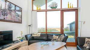 Ein modernes Wohnzimmer mit einer Ledersofa, einem Holztisch und einem Fernseher.