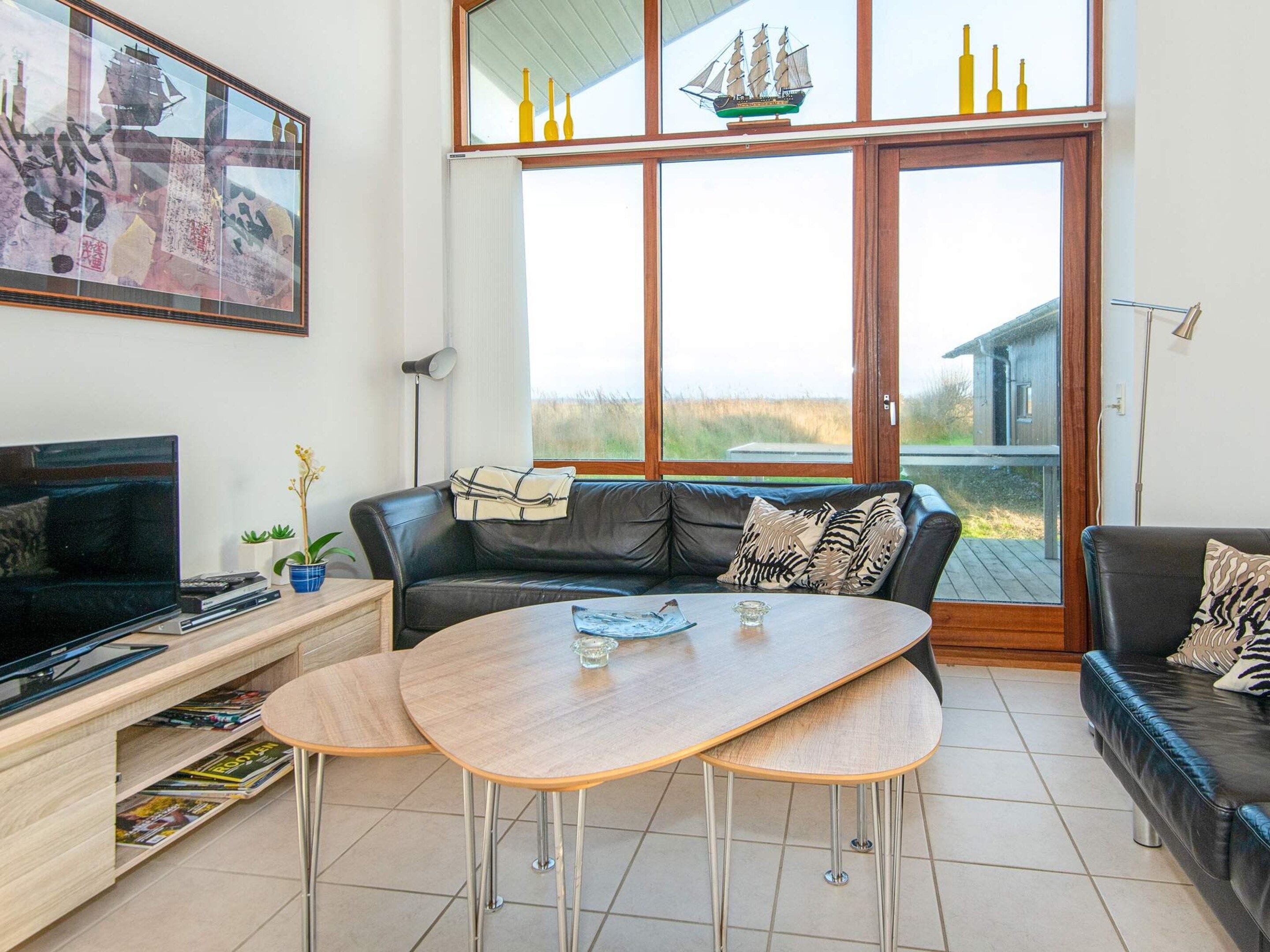Een woonkamer met een leren bank, een houten salontafel, een televisie en een boekenkast.