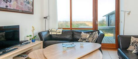Een woonkamer met een leren bank, een houten salontafel, een televisie en een boekenkast.