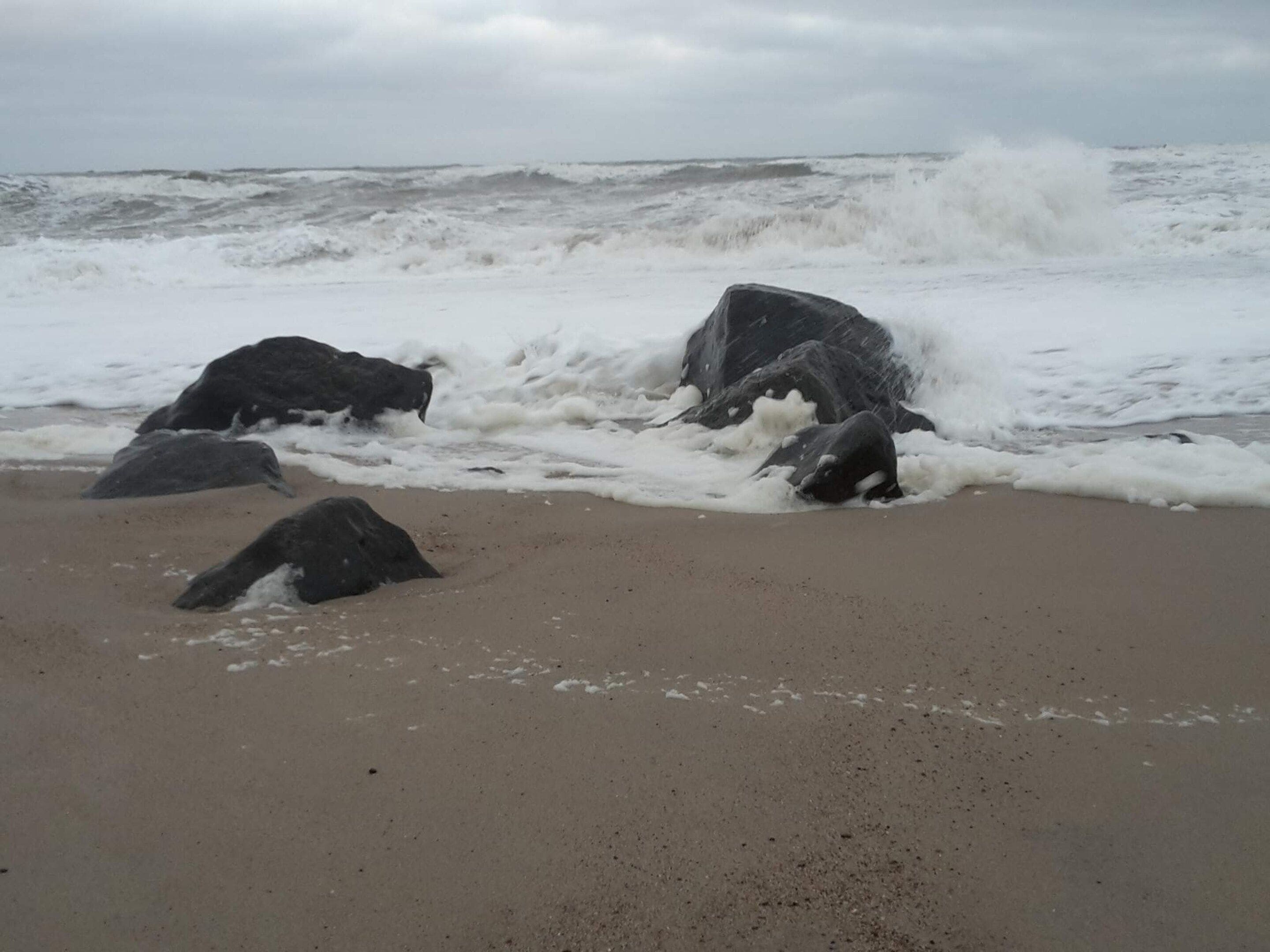A beach with large rocks and rough waves.