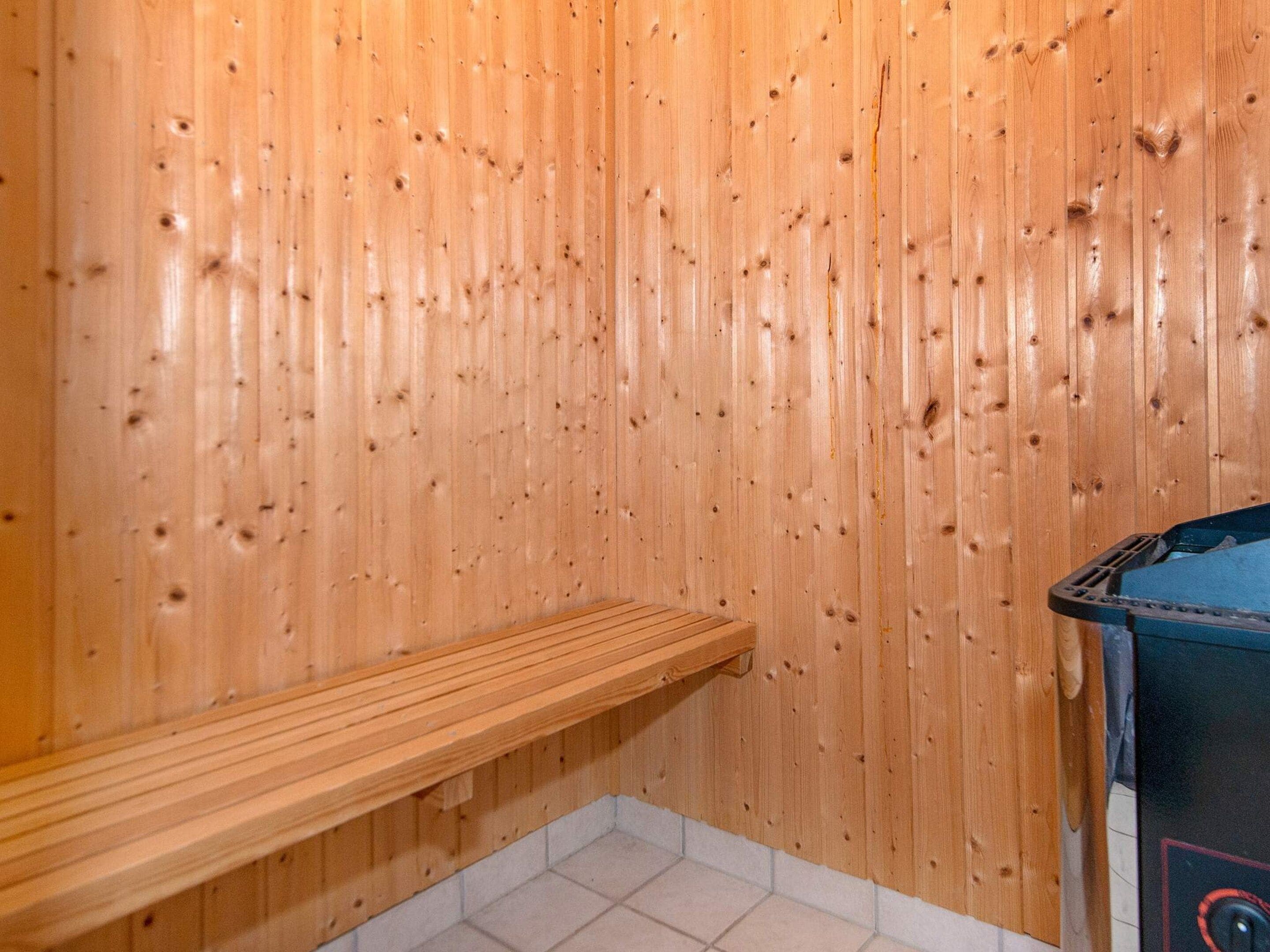A sauna room with wooden walls, a bench, and a sauna machine.
