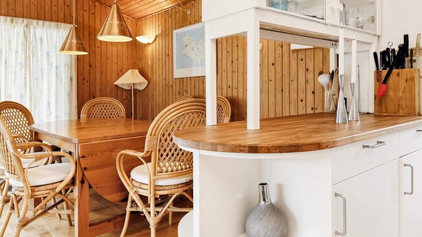 Un interior de madera con comedor, armarios blancos y una encimera de cocina.
