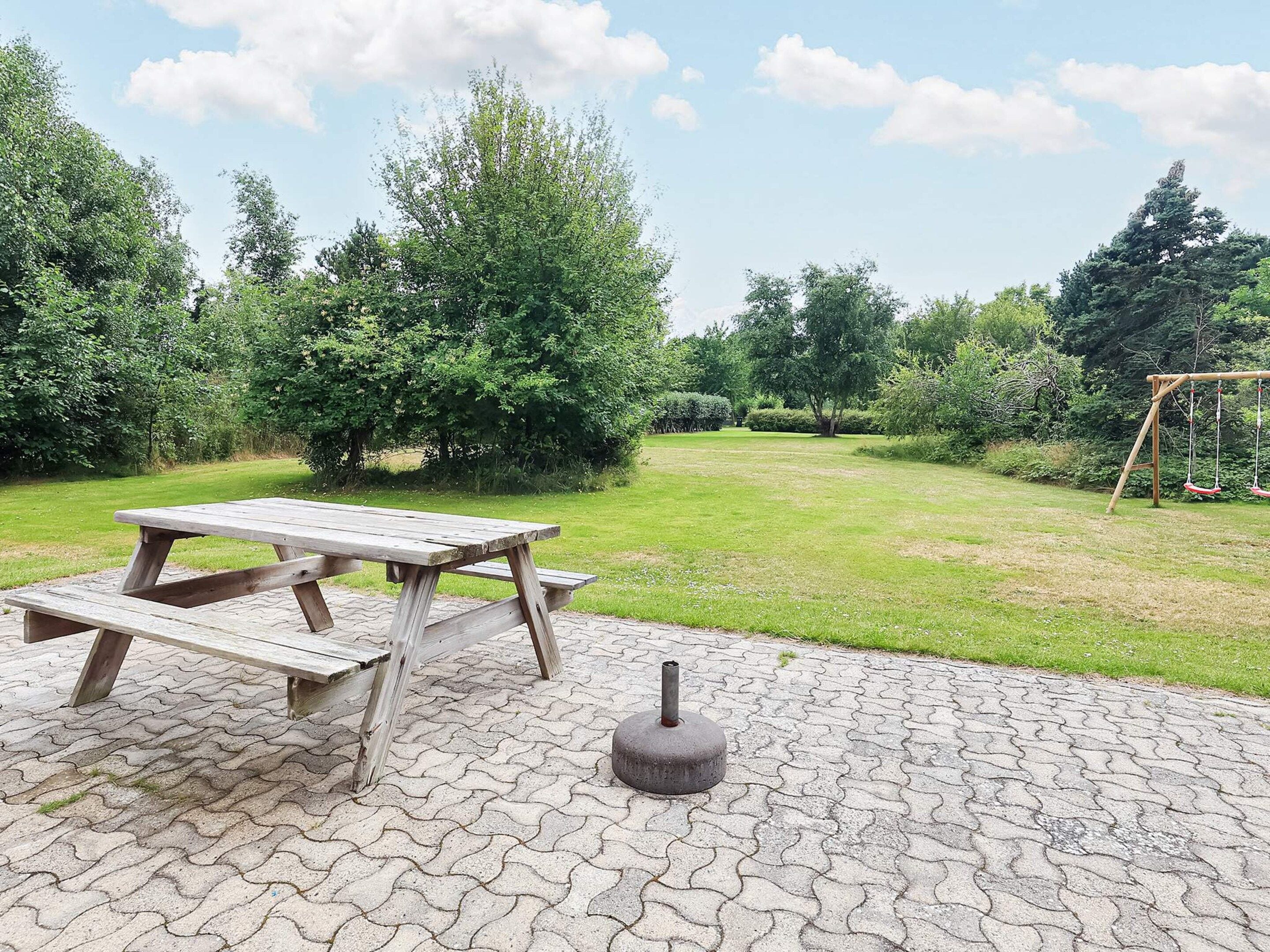 Ett picknickbord med bänkar och en betongstolpe på en gräsig utomhusplats.