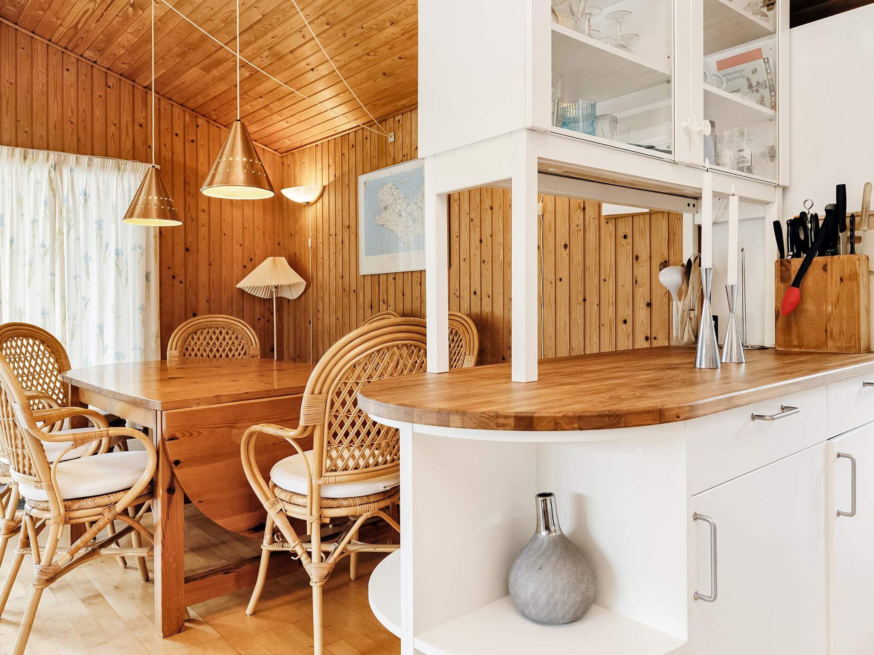 A wooden interior with a dining area, white cabinets, and a kitchen counter.