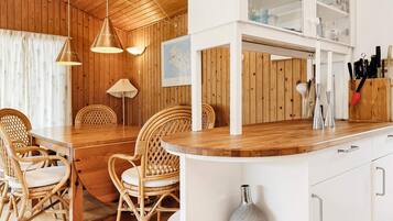 A wooden interior with a dining area, white cabinets, and a kitchen counter.