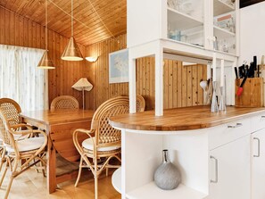 A wooden interior with a dining area, white cabinets, and a kitchen counter. - 8 Person Holiday Home in Dannemare (Dannemare)