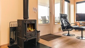 A cozy room with a wood-burning stove, a comfortable chair, and a television. - 8 Person Holiday Home in Vestervig-by Traum (Vestervig)