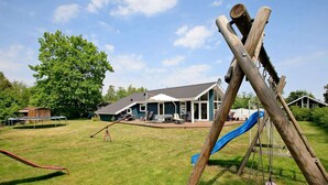 A backyard with a swing set, a slide, and a trampoline. - Serene Holiday Home in Juelsminde near Beach (Juelsminde)