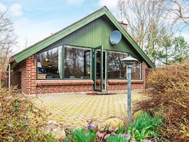A brick house with a green roof, large windows, and a satellite dish.