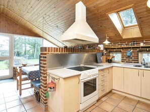 A kitchen with a central island, a stove, and a large window. - Rustic Holiday Home in Jutland near Sea (Ulfborg)