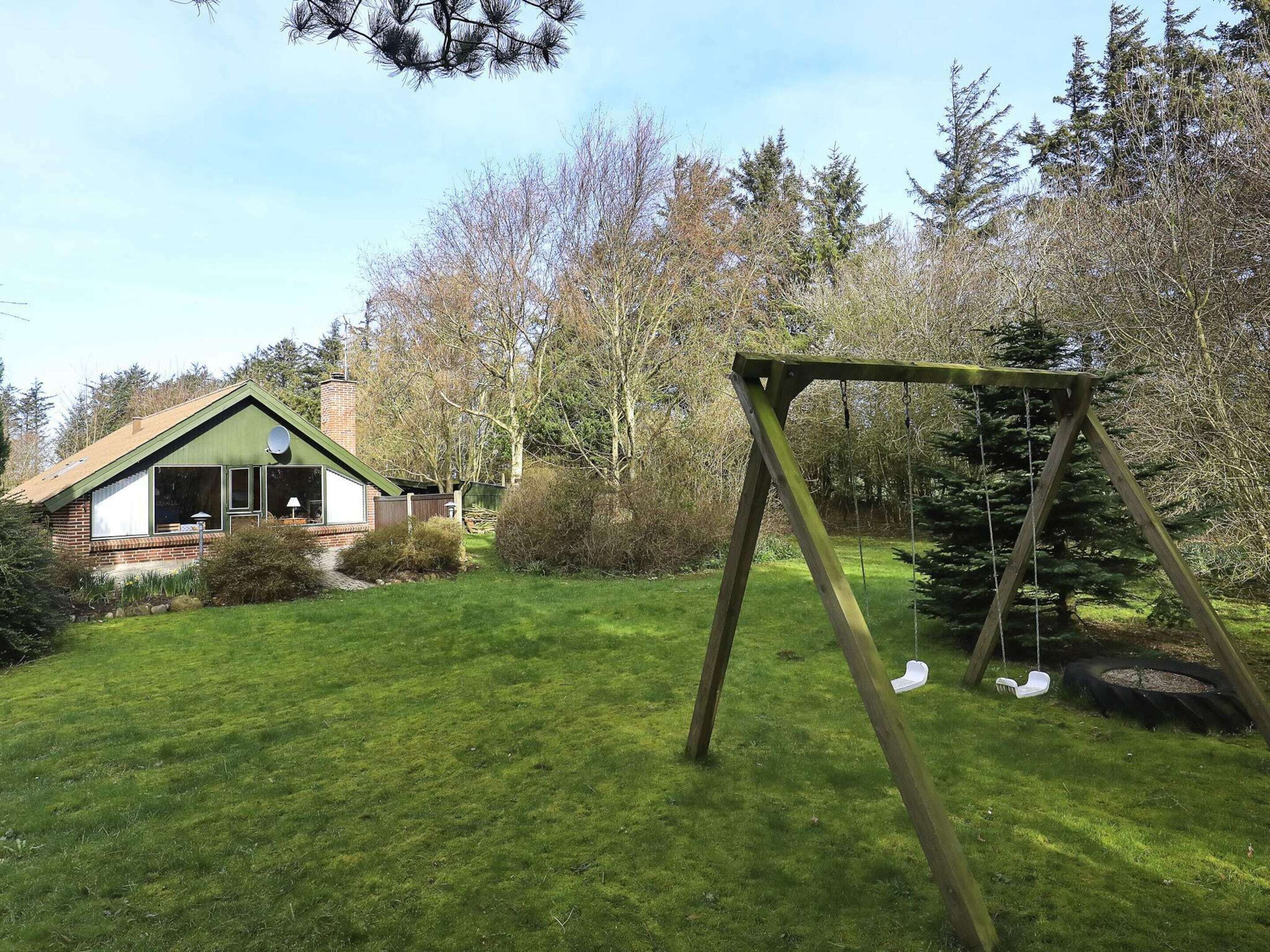 A house with a green roof, a swing set, and a well-maintained lawn.