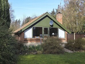 A house with a green roof, brick walls, and a satellite dish.