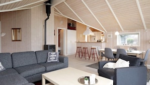 A modern living room with a grey sofa, a coffee table, and a dining area with a table and chairs.