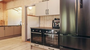 Een keuken met houten kastjes, een Bosch oven, een roestvrijstalen koelkast en een broodrooster.