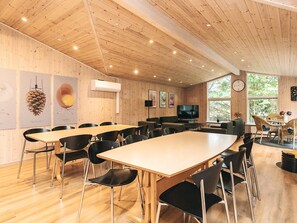 A spacious room with a long table, multiple chairs, a television, and a clock on the wall. - 4 Star Holiday Home in Oster Assels (Øster Assels)