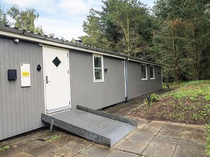 A single-story building with a grey exterior, a white door, and a small window. - 4 Star Holiday Home in Oster Assels (Øster Assels)