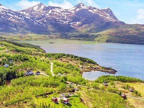 A lakeside village with houses, a dock, and mountains in the background.