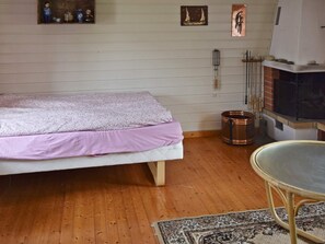 Un dormitorio con cama, una mesita, chimenea y piso de madera.