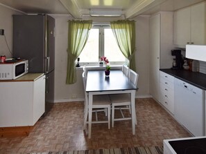 Een keuken met een eettafel, stoelen, een magnetron en een koelkast.