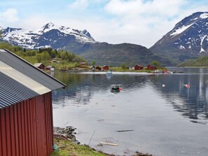 A lakeside view with a red building, boats, and mountains in the background.