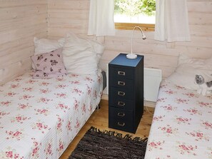 A small, cozy bedroom with two beds, a dresser, and a window with curtains. - Holiday Home in Tyringe (Tyringe)