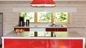 A modern kitchen with a red island, stainless steel appliances, and a window providing natural light.