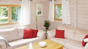 A cozy living room with two cream sofas, red cushions, a wooden coffee table, and a vase with flowers.