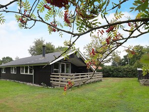 A wooden cabin with a sloped roof, a porch, and a chimney.