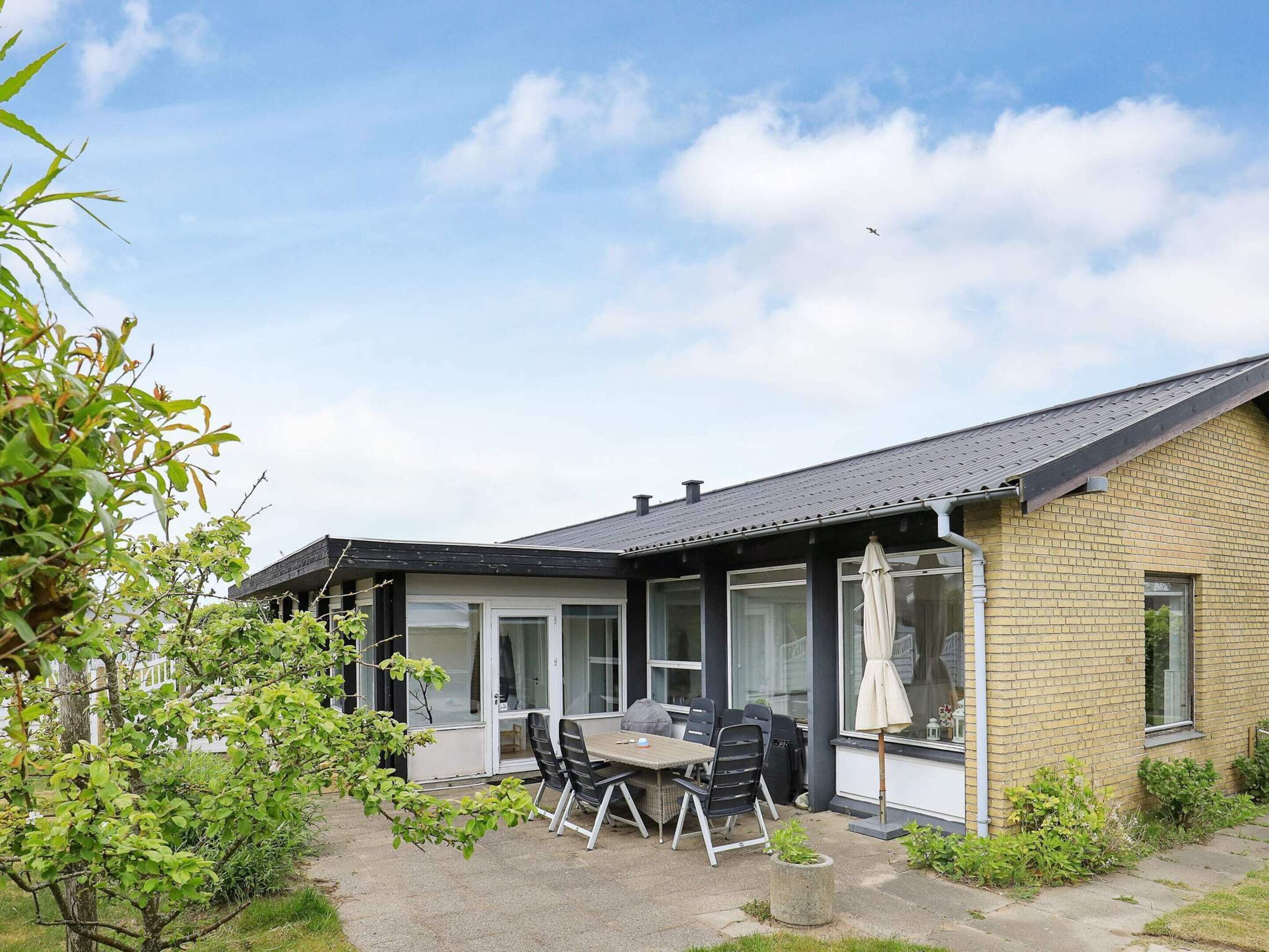 Et toetagers hus med en patio, hvor der er borde og stole.
