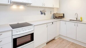Una cocina moderna con armarios blancos, horno empotrado, microondas y fregadero.