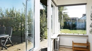 Una habitación moderna con un gran ventanal corredero que da a un espacio exterior con una mesa y sillas.