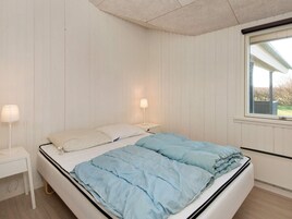Un dormitorio con cama, lámparas de noche y ventana.
