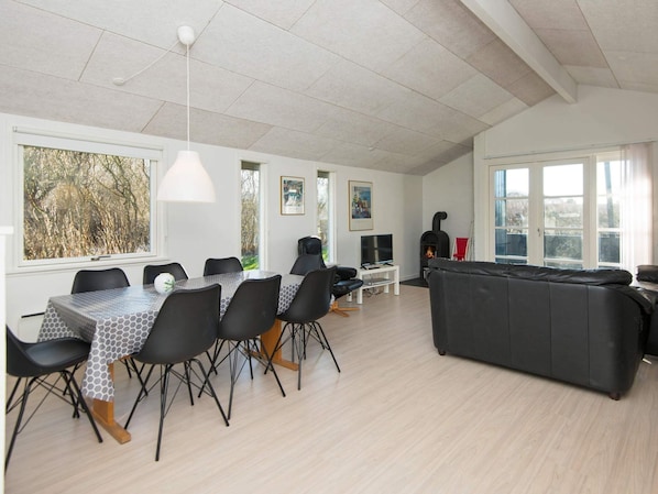 A spacious living area with a dining table, chairs, a sofa, a fireplace, and large windows. - 8 Person Holiday Home in Borkop (Borkop)