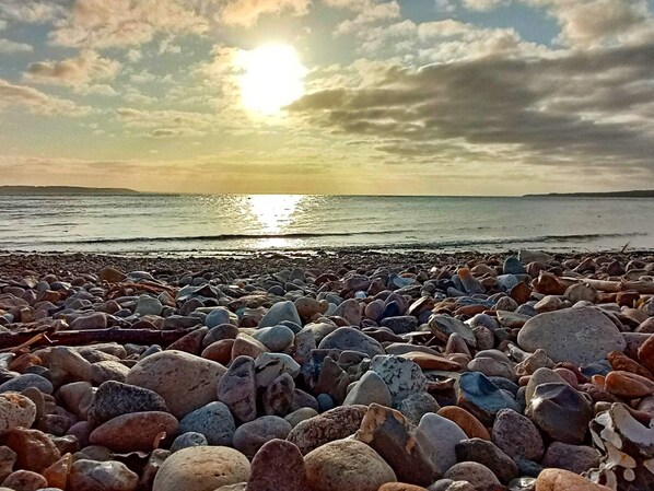 Ein felsiger Strand mit Sonnenuntergang über dem Wasser.