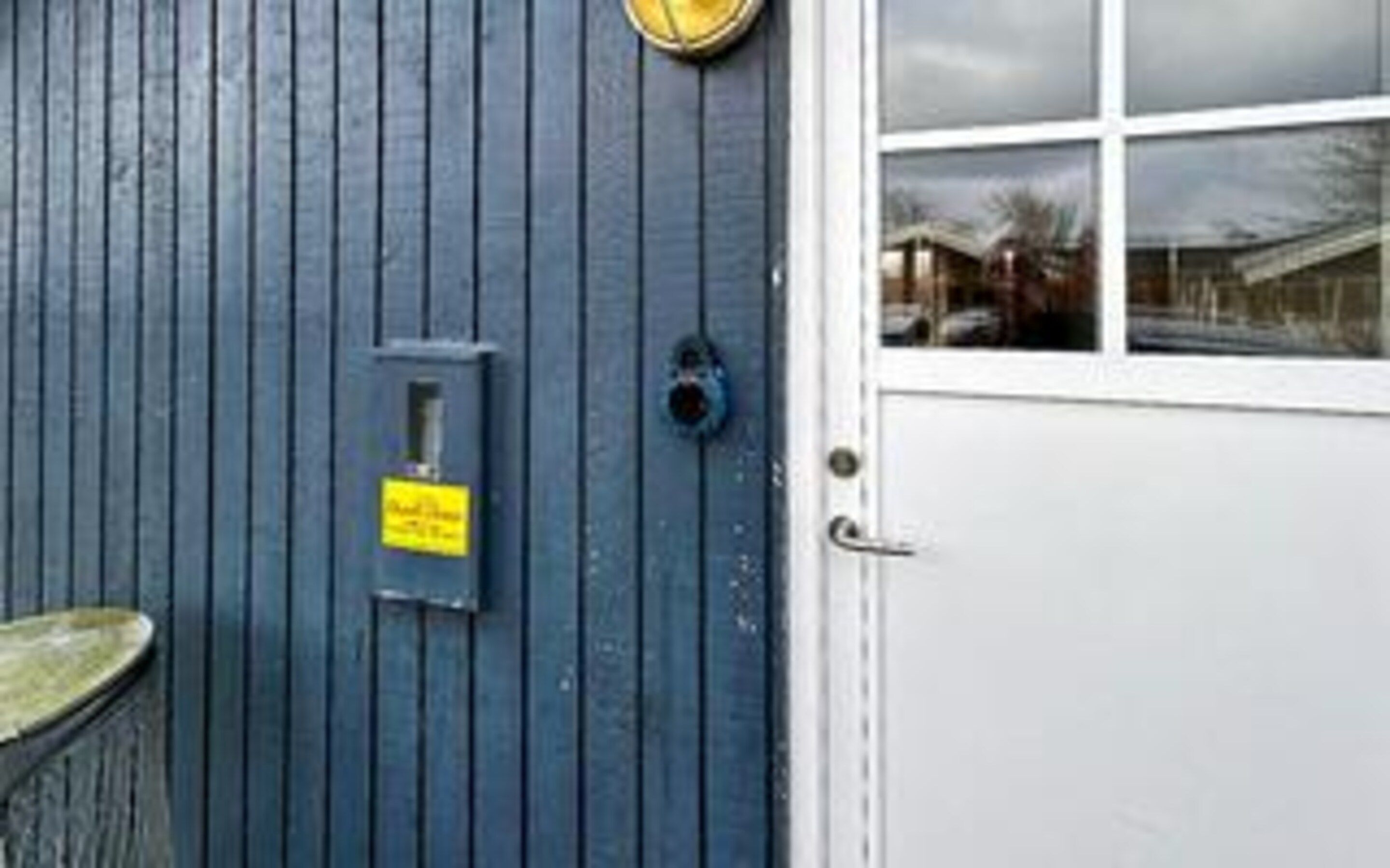 Una porta blu con un cartello giallo, una finestra e una maniglia di metallo.