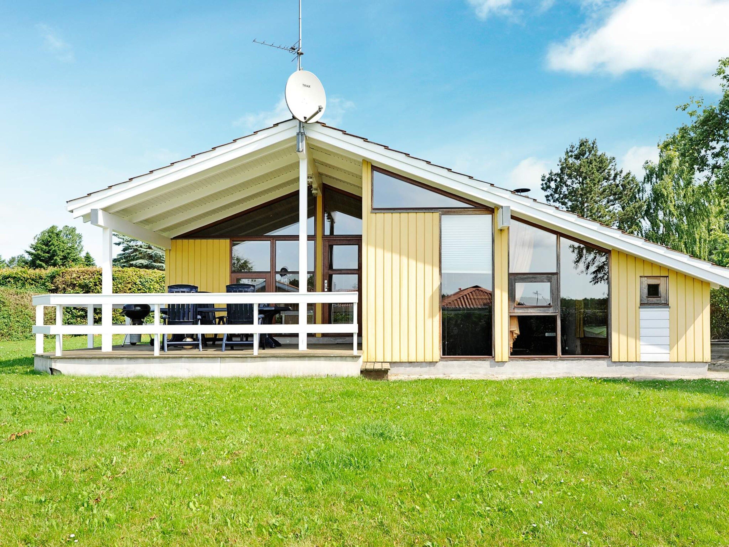 Une maison moderne avec un toit en pente, de grandes fenêtres et une antenne parabolique.