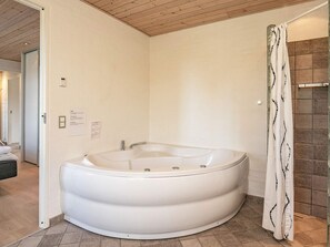 Un baño moderno con una bañera independiente, un cortinón de ducha y suelo de baldosas.
