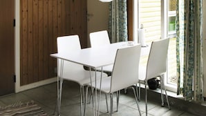 Un'area pranzo con tavolo e sedie bianche, un lampadario e una finestra con tende.