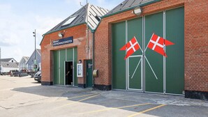 Un edificio con due porte per garage verdi, un cartello con la scritta 