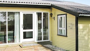 Una casa gialla con patio in mattoni, una porta scorrevole in vetro e una piccola finestra.