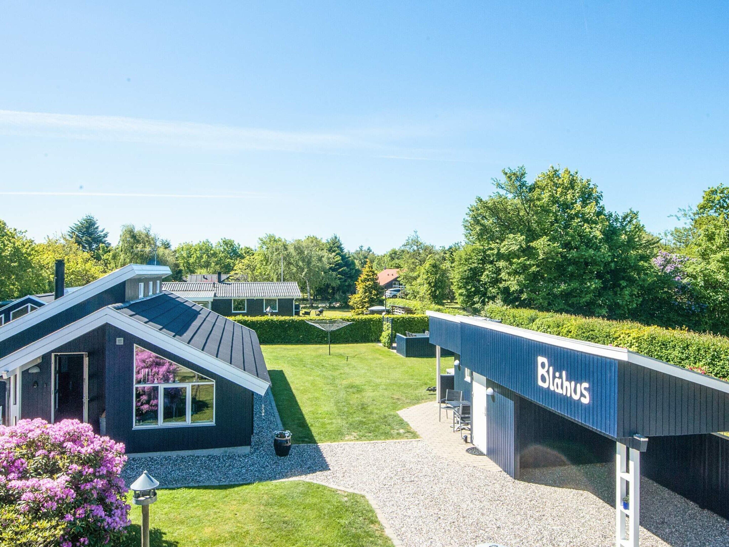 A modern building with a sign reading 'Blahus,' a well-maintained lawn, and a clear sky.