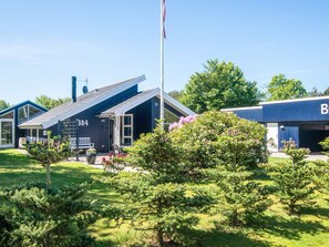A building with a number '384' on the side, a flagpole, and a well-maintained lawn with shrubs. - Captivating Holiday Home in Ulfborg near Sea (Ulfborg)