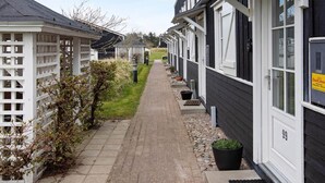 Eine Reihe moderner, dunkel gefasster Gebäude mit weißen Geländern und einem gepflasterten Weg.