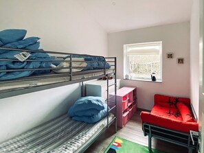 A dormitory room with bunk beds, a small desk, a red chair, and a window with a view. - Woodland Holiday Home in Jægerspris with Hot Tub (Jægerspris)