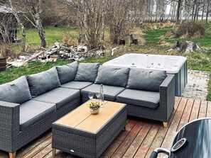 A sectional sofa with cushions and a wooden table with a vase of flowers. - Woodland Holiday Home in Jægerspris with Hot Tub (Jægerspris)