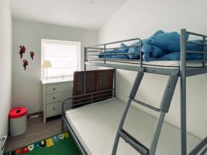 A bunk bed room with a window, a desk, and a trash bin.