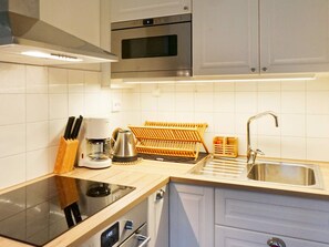 A modern kitchen with a built-in oven, a coffee maker, and a kettle on the countertop.