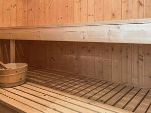 A sauna with wooden benches and a wooden bucket.